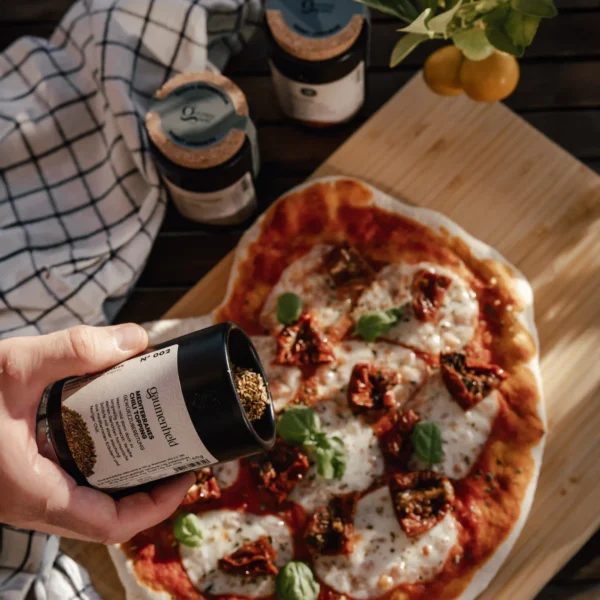 Mediterranes Chili Topping wird auf Pizza gestreut