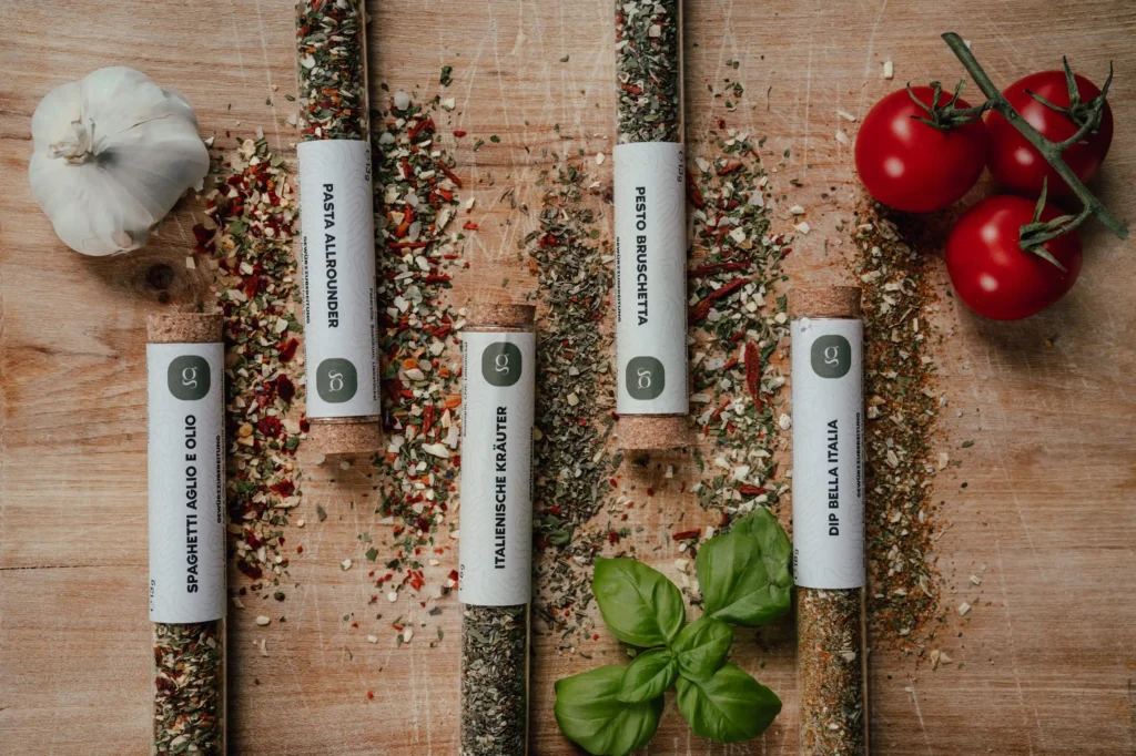 Gaumenheld Gewürze auf einem Holzbrett mit Knoblauch, Tomaten und Basilikum